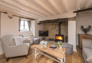 A cozy living room with a stone fireplace, wooden beams, and comfortable seating.