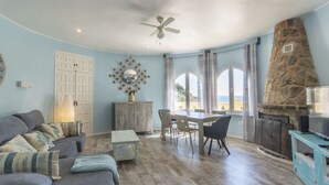 A living room with a sofa, a dining table with chairs, a ceiling fan, and a stone fireplace. - Villa Ronda - Costa CarpeDiem (Calpe)