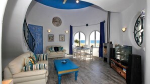 A living room with a sofa, coffee table, TV, and dining area with chairs and a table. - Villa Ronda - Costa CarpeDiem (Calpe)