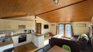 Un interior de cabaña acogedor con cocina, comedor y sofá.