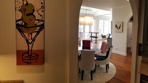 Een moderne eetruimte met een ronde tafel en stoelen, een kroonluchter en een schilderij aan de muur.
