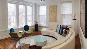 Een moderne woonkamer met een gebogen modulaire bank, een ronde salontafel en een plafondventilator.