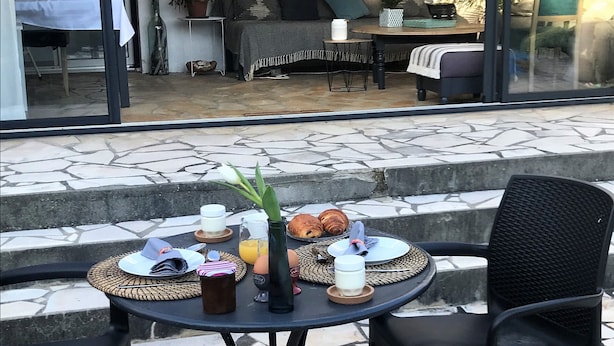 Un espacio exterior para comer con una mesa dispuesta para el desayuno, que incluye cruasanes, huevos y jugo.