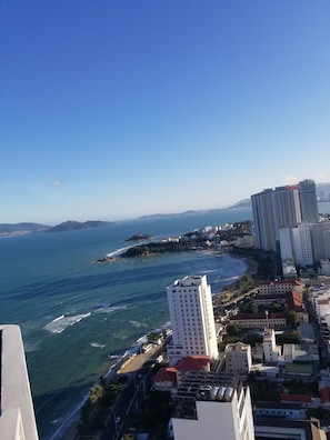 A coastal cityscape with high-rise buildings, a beach, and a clear blue sky. - Luxury Scenia Bay Apartment with Seaview (Bac Nha Trang)