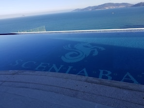 A infinity pool with a view of the ocean and distant mountains. - Luxury Scenia Bay Apartment with Seaview (Bac Nha Trang)