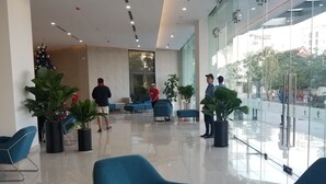 A modern lobby with blue chairs, a marble table, and potted plants.