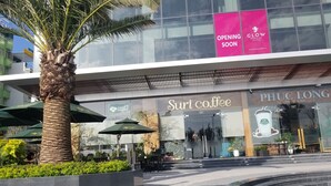 A modern building with a glass facade, featuring signage for 'Suri Coffee' and 'PHUC LONG Coffee & Tea'.