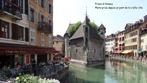 A historic stone building with a tower, surrounded by a canal and colorful buildings. - Large studio in the center of Annecy (Annecy)