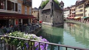 A historic stone building with a tower, surrounded by a canal and colorful buildings.