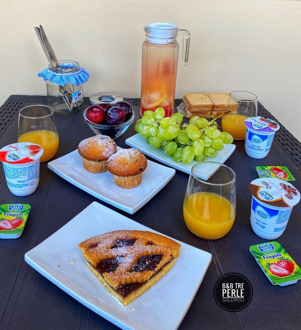 A breakfast table with various food items including pastries, fruit, and beverages. - Tre Perle (Gallipoli)