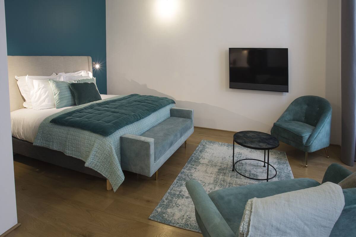 A modern bedroom with a bed, a TV, and a seating area.