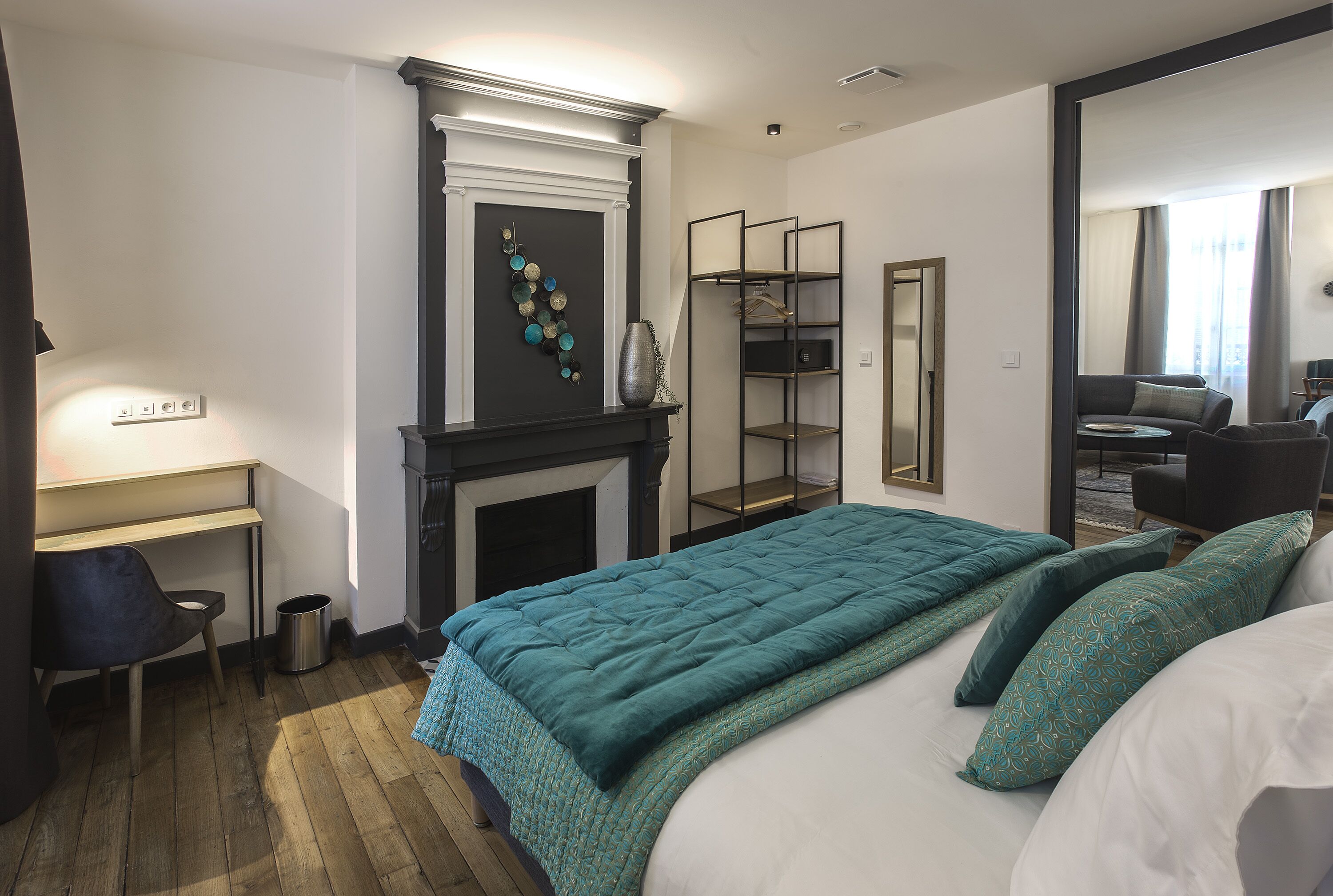 Un dormitorio con cama, escritorio, chimenea y espejo.