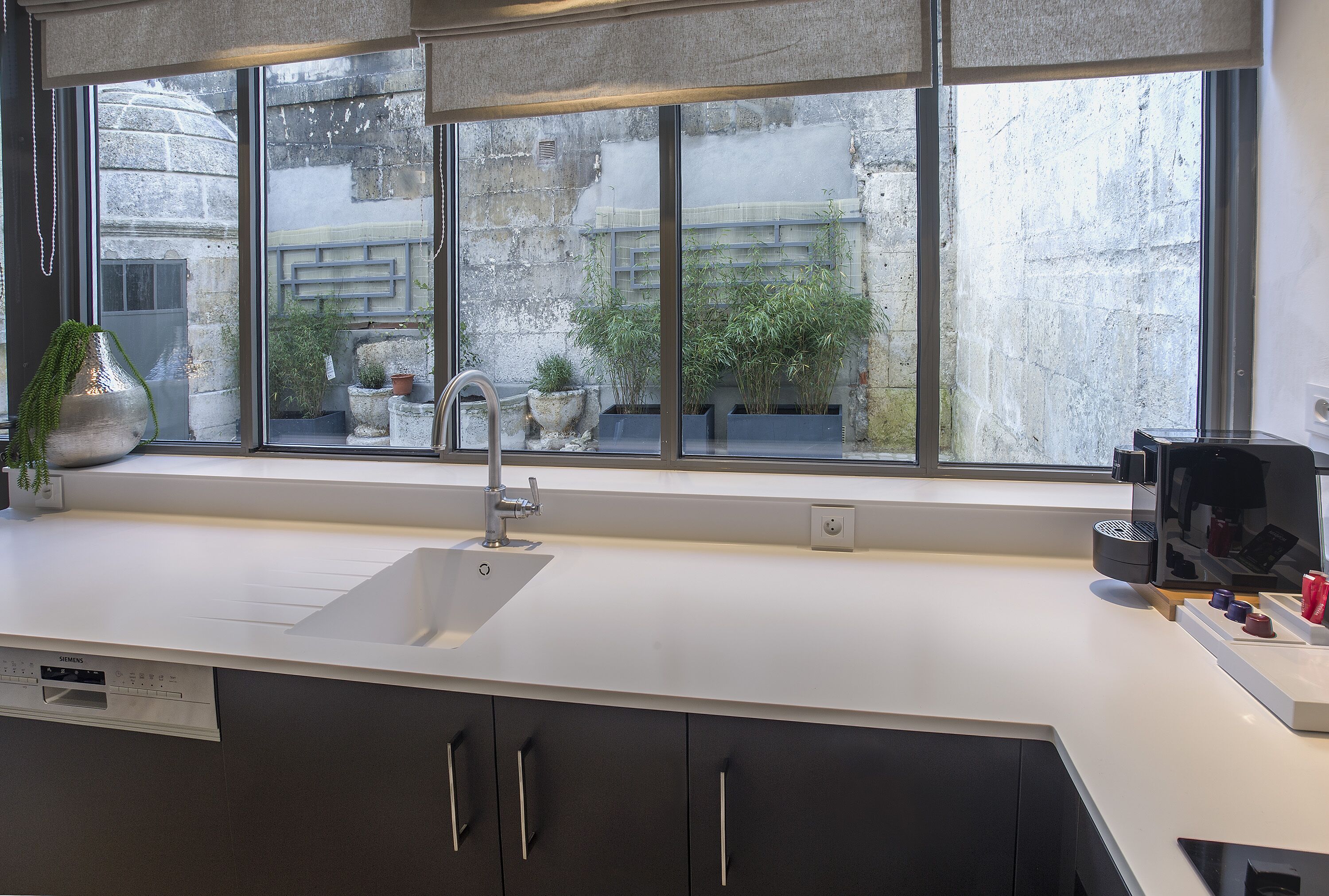 A modern kitchen with a large window, a built-in sink, and a dishwasher.