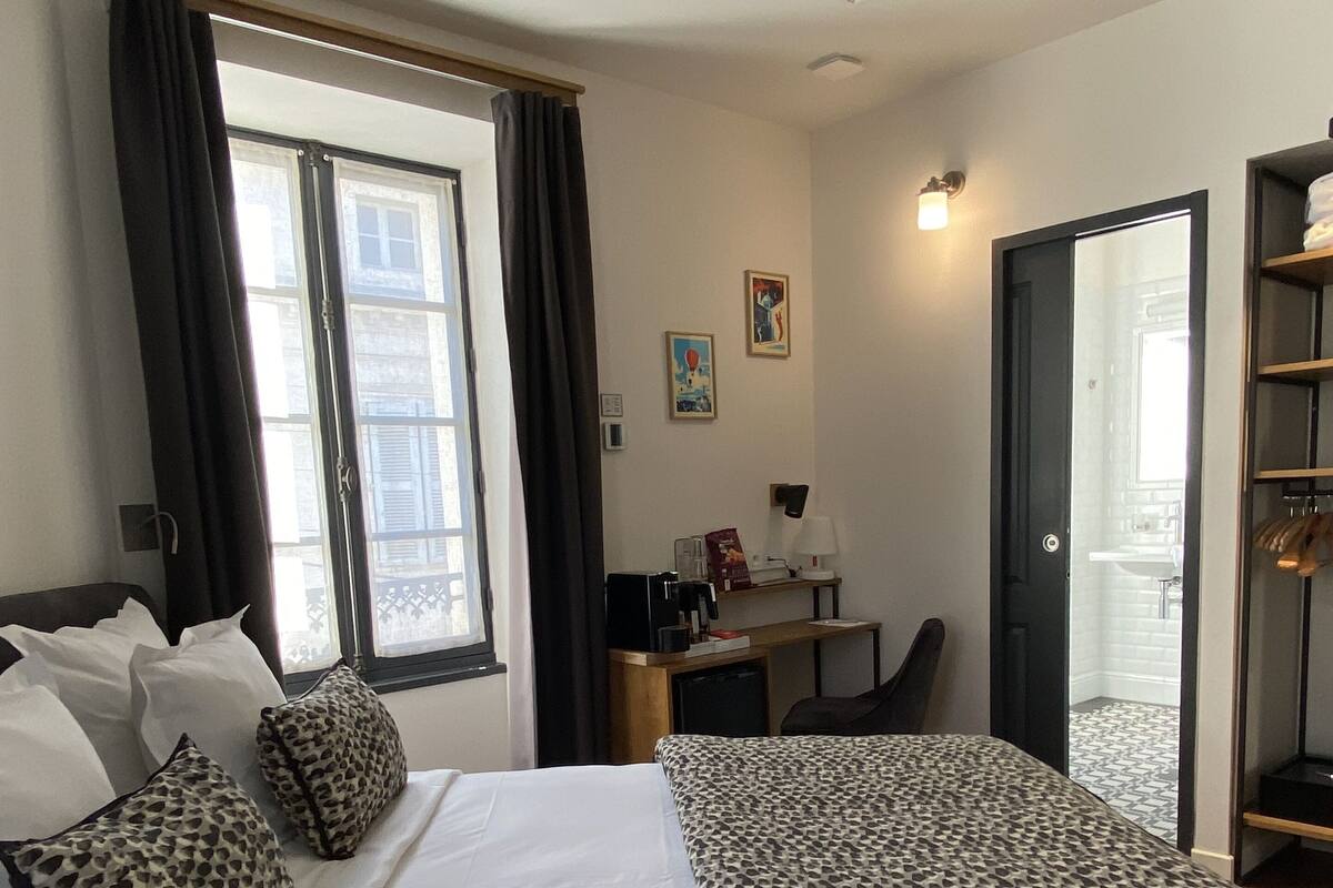 A hotel room with a bed, a desk, and a wardrobe.