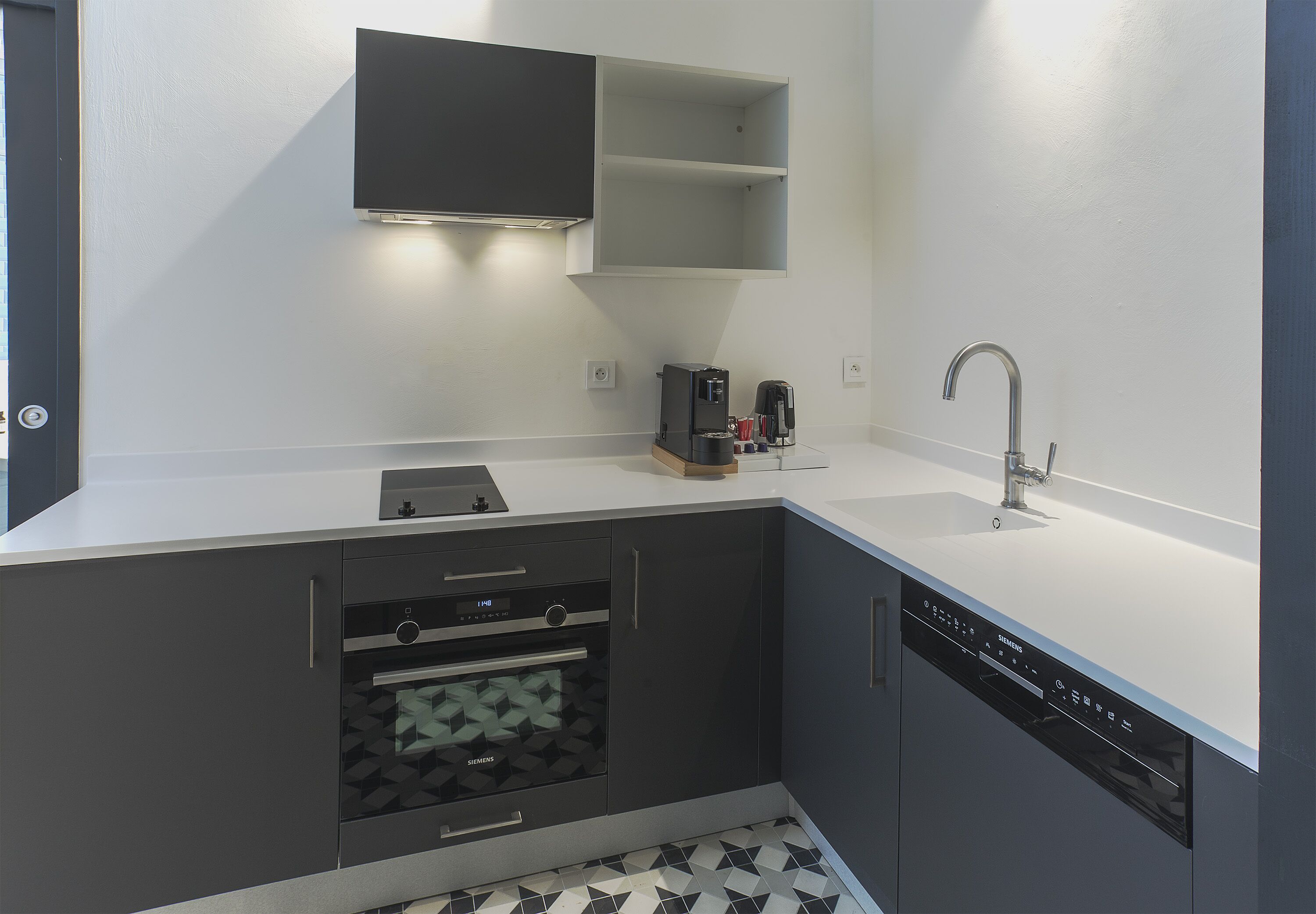 A modern kitchen with grey cabinetry, a built-in oven, a coffee machine, and a dishwasher.