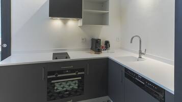 A modern kitchen with grey cabinetry, a built-in oven, a coffee machine, and a dishwasher.