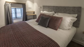Una cama bien hecha con ropa de cama estampada, un cabecero y una mesita de noche con una lámpara.
