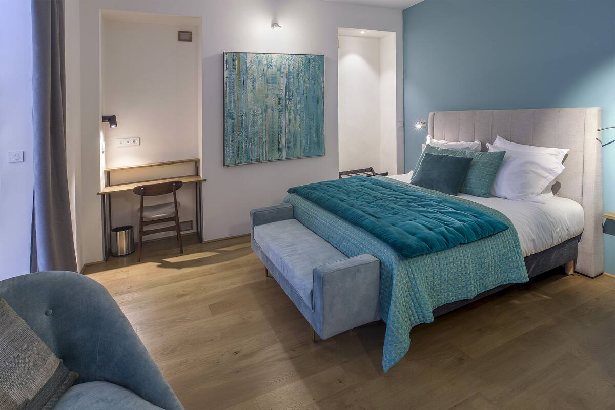 A bedroom with a bed, a desk, and a chair.