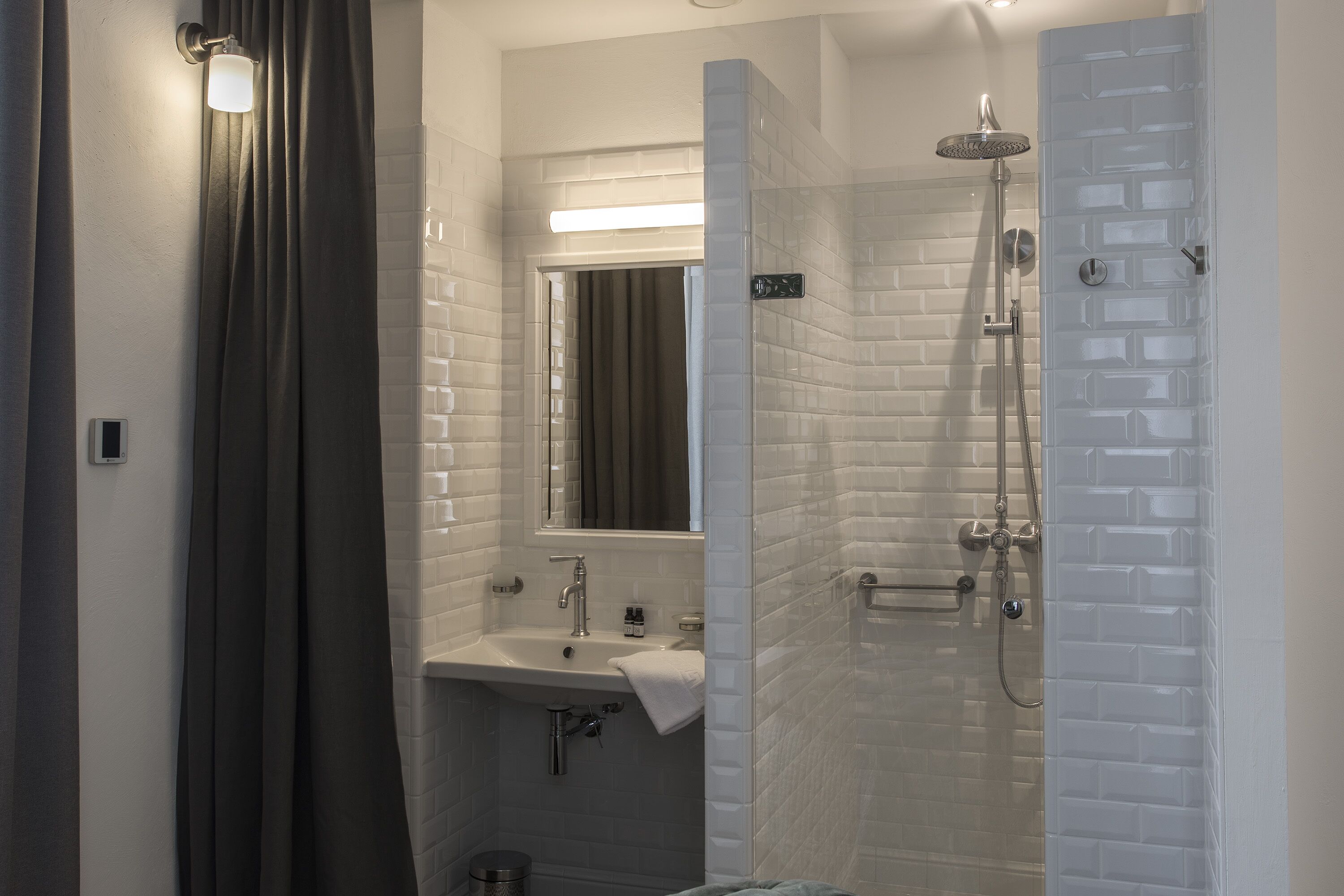 A modern bathroom with a glass shower enclosure, a sink with a mirror, and a towel hanging on the wall.