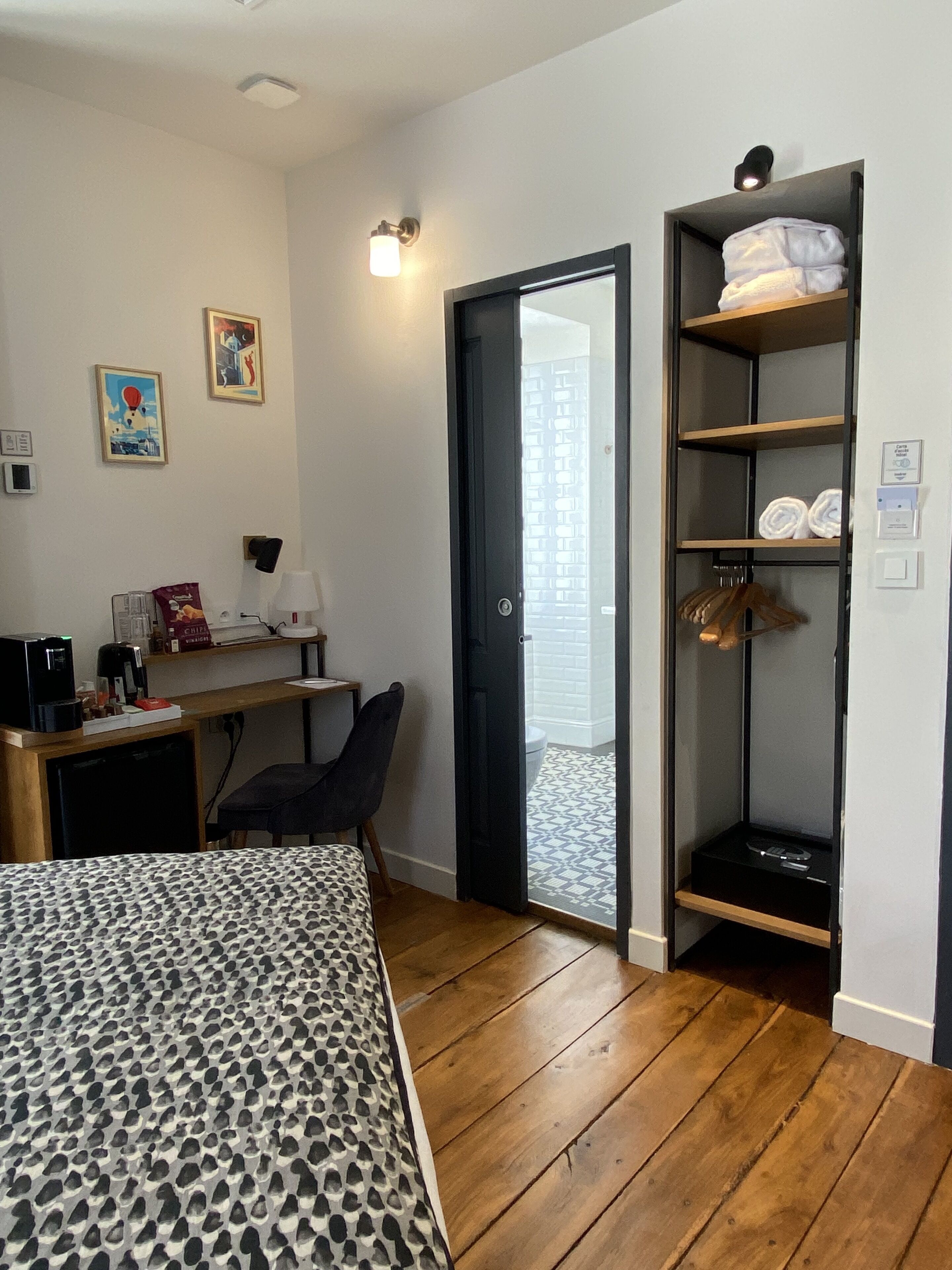A bedroom with a bed, a desk, a chair, a wardrobe, and a door leading to a bathroom.