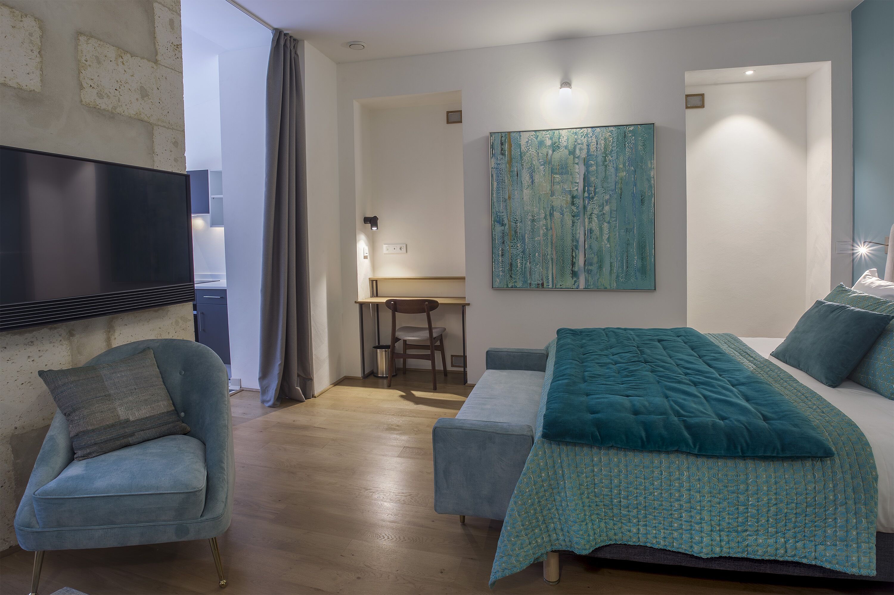 Un dormitorio moderno con una cama, una silla, un escritorio y un cuadro en la pared.