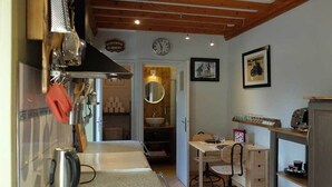 A compact kitchen with a kettle, a sink, and a dining area with a chair and table.