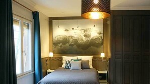 A bedroom with a large bed, a wall-mounted artwork, and a dark wooden wardrobe.