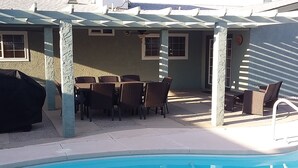 Un espace piscine agrémenté d’une pergola, de coins salon extérieurs et d’un barbecue.
