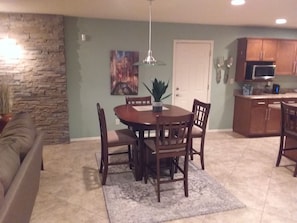 Un coin repas avec une table ronde, quatre chaises, une plante en pot et un tableau accroché au mur.