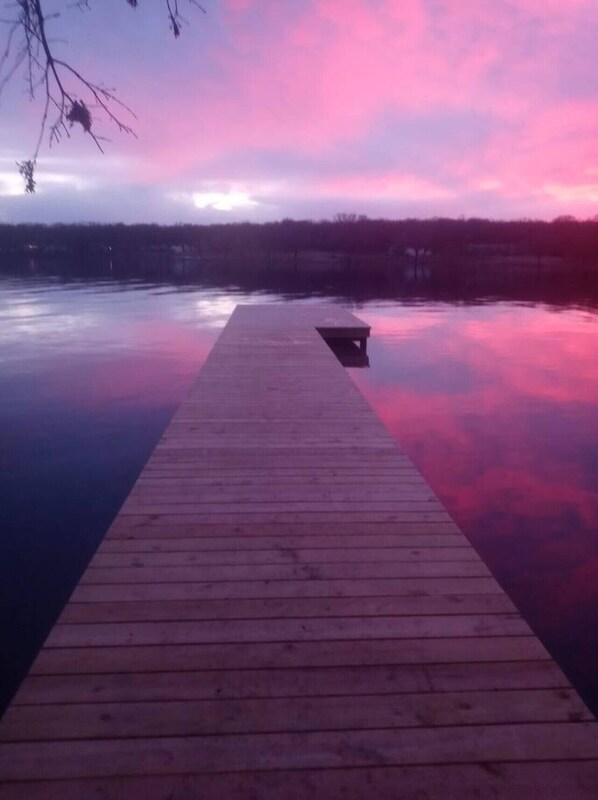 A wooden pier extending into calm water with a sunset sky.