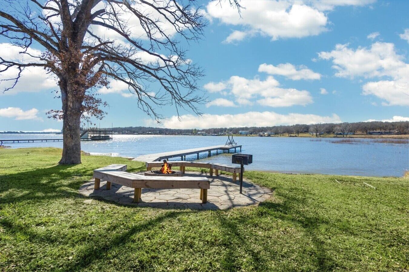 Un espace de pique-nique au bord du lac, équipé d’un foyer, de bancs et d’une jetée qui s’avance dans l’eau.