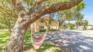 A hammock hanging from a tree in a residential area with houses in the background. - Beach Life, ground floor, quiet &clean. 2BR 2 Bath (Saint Augustine)