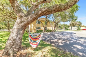 Relax in a hammock suspended from a tree, overlooking a residential area with a building in the distance.