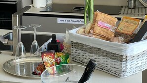 Un comptoir de cuisine avec un panier de pain, une bouteille de champagne, un vase rempli de fleurs et un plateau avec des verres.