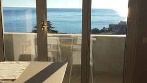 Une pièce dotée d’une porte-fenêtre coulissante donnant sur un balcon avec vue sur la mer.