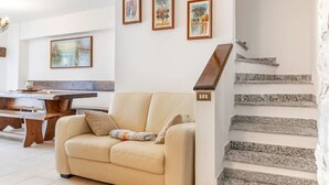 A living room with a beige sofa, a wooden coffee table, and a staircase with stone steps. - Art Nature and Tranquility (casalzuigno)