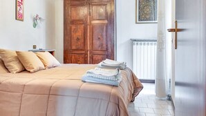 A bedroom with a bed, pillows, a radiator, and a wooden door. - Art Nature and Tranquility (casalzuigno)