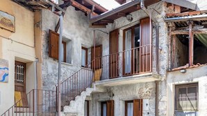 A multi-story building with a stone facade, wooden shutters, and a metal staircase. - Art Nature and Tranquility (casalzuigno)