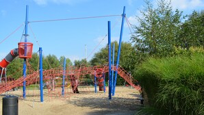 Une aire de jeux avec des structures d’escalade et une balançoire.