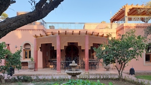 Une cour agrémentée d’une pergola, d’un espace salon extérieur, d’une fontaine et d’une végétation luxuriante.
