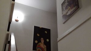 Un escalier avec une rampe en bois mène à un palier où un tableau est accroché au mur.