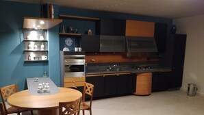 Une cuisine moderne avec un coin repas. Elle comprend une table ronde avec des chaises, un four encastré et un évier.