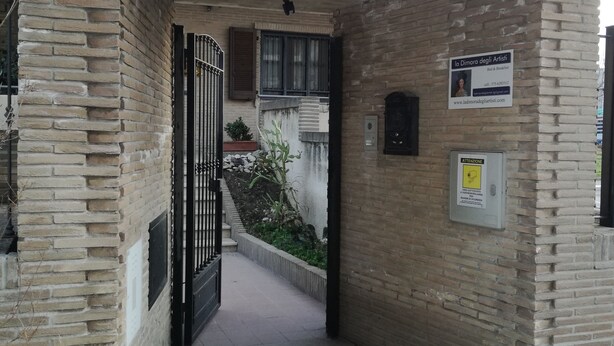 Une entrée avec une arche en briques, un portail et un panneau indicateur.