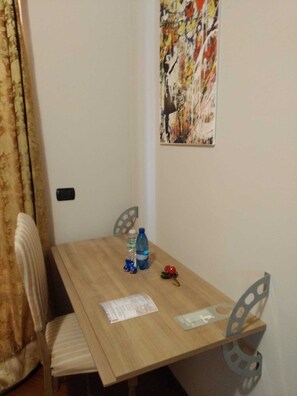 Un pequeño comedor con una mesa de madera, dos sillas, una botella de agua y un adorno.