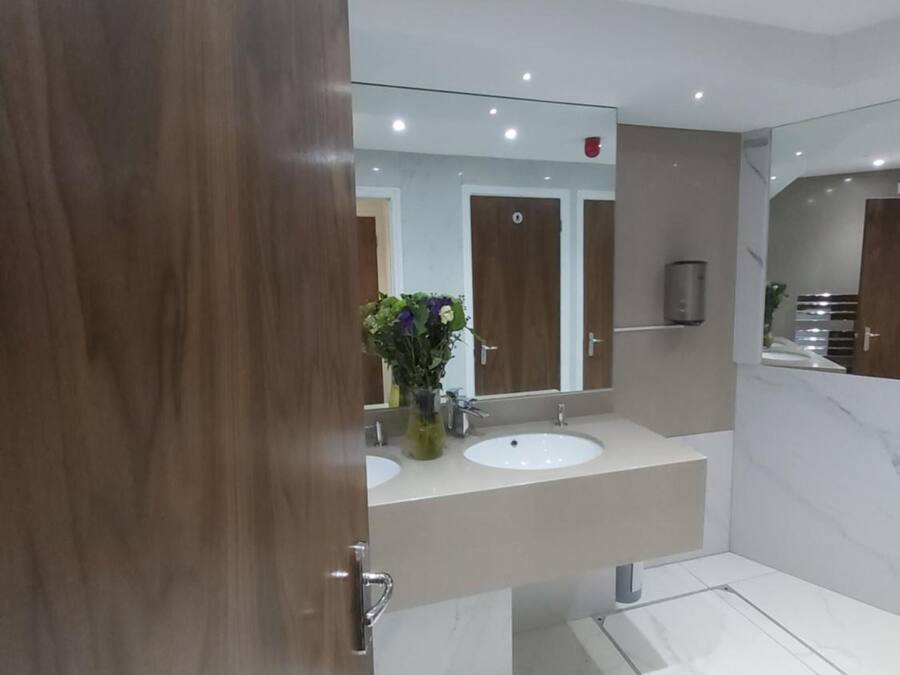 Un baño moderno con dos lavamanos, un espejo grande y una zona de ducha.