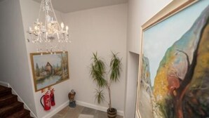 Uma escadaria com um candelabro, um quadro e duas plantas em vasos.