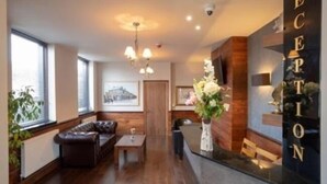 A reception area with a reception desk, a sofa, and a coffee table. - Eagle Hotel (Luton)