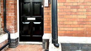 Puerta doble negra con una placa con el número '77' y un letrero en la pared que dice 'Switchback Stays'.