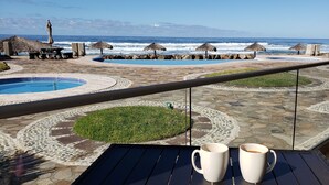 Un espace aménagé au bord de la piscine, avec vue sur l’océan, une table basse et deux tasses blanches.