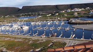 Un port de plaisance avec des bateaux amarrés, un port et un paysage montagneux en arrière-plan.